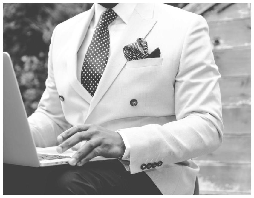 Black and white photo of a man in a suit typing on