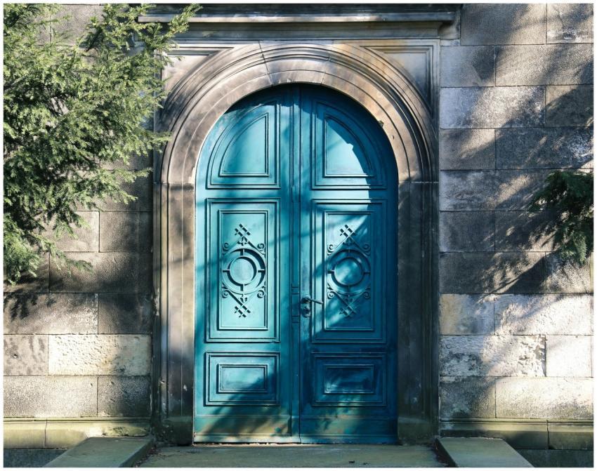 A vibrant blue arched door with gothic designs. Sh