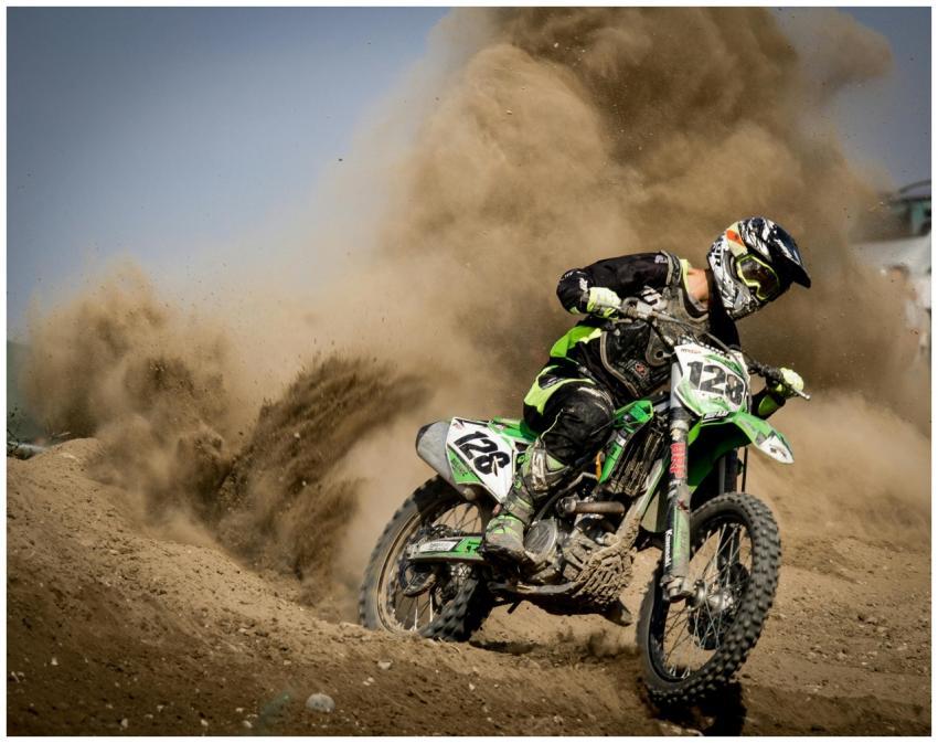 A thrilling motocross rider powers through dust in