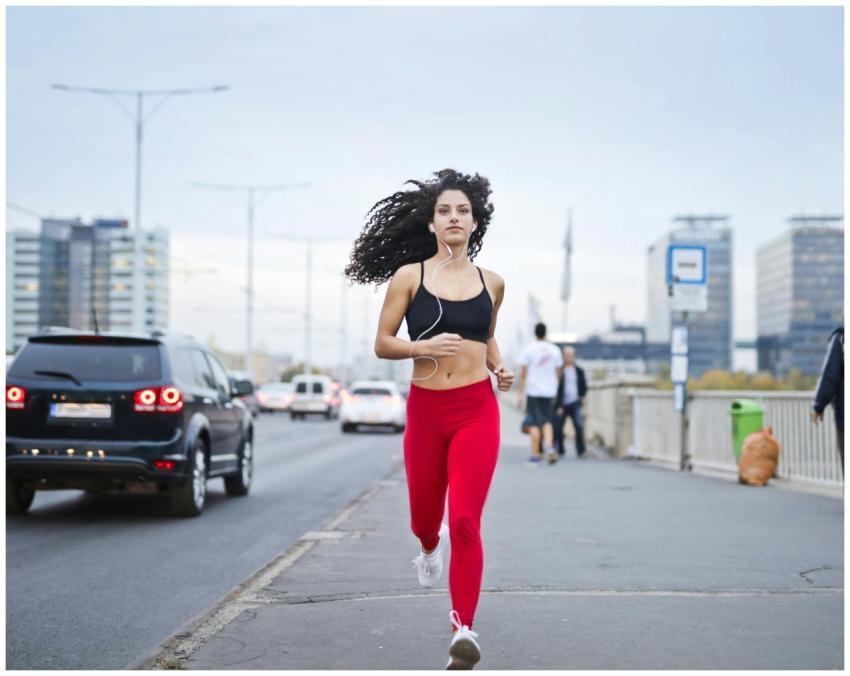 A fit woman with curly hair runs on a city street,