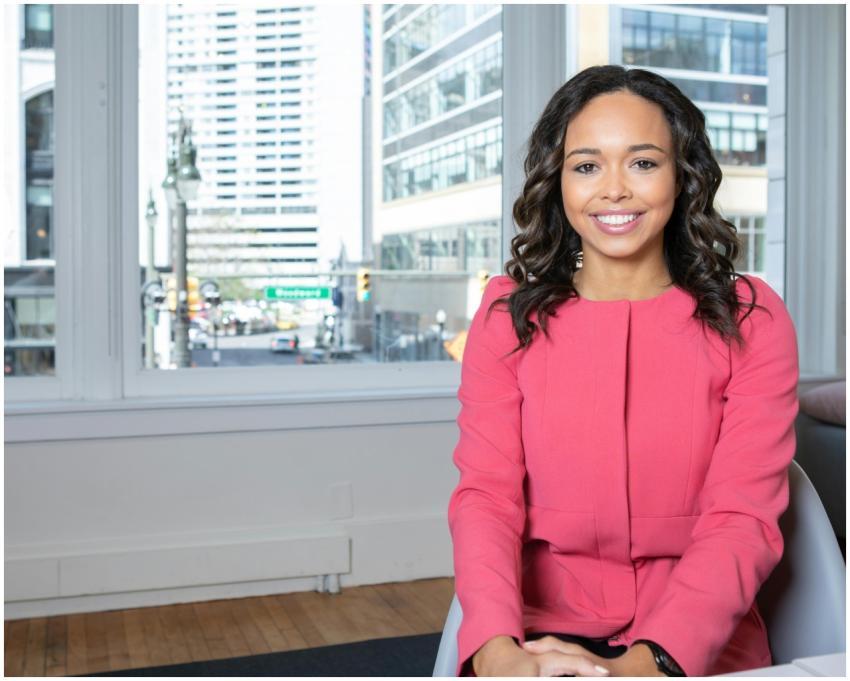 Young woman in a pink blazer smiles confidently in