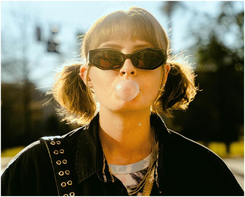Stylish young woman with sunglasses blowing bubble