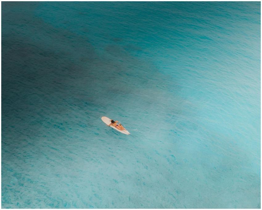 A lone surfer paddles on a surfboard across the cl