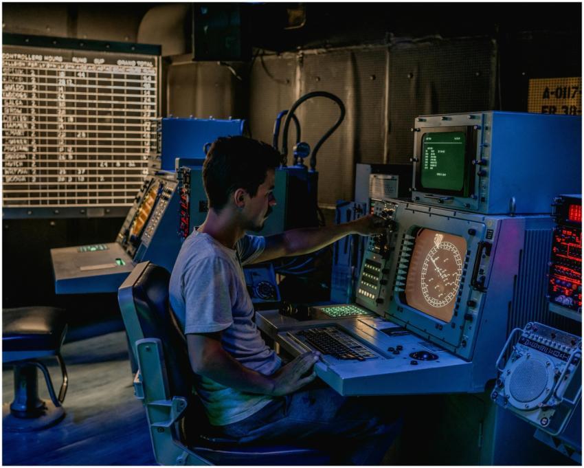 A man working at control panels in a dimly lit ind