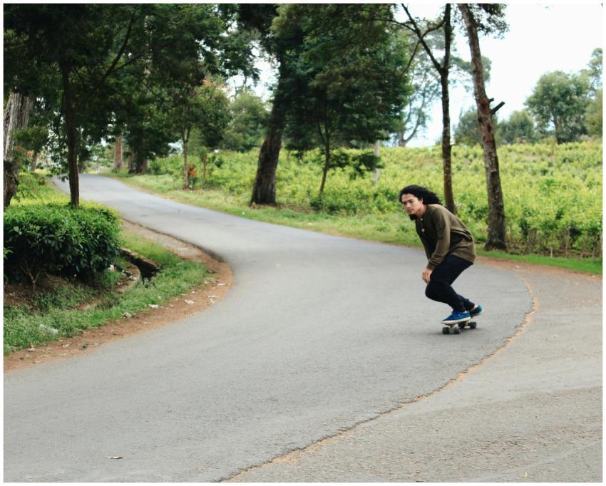 A young man skateboards along a scenic tree-lined