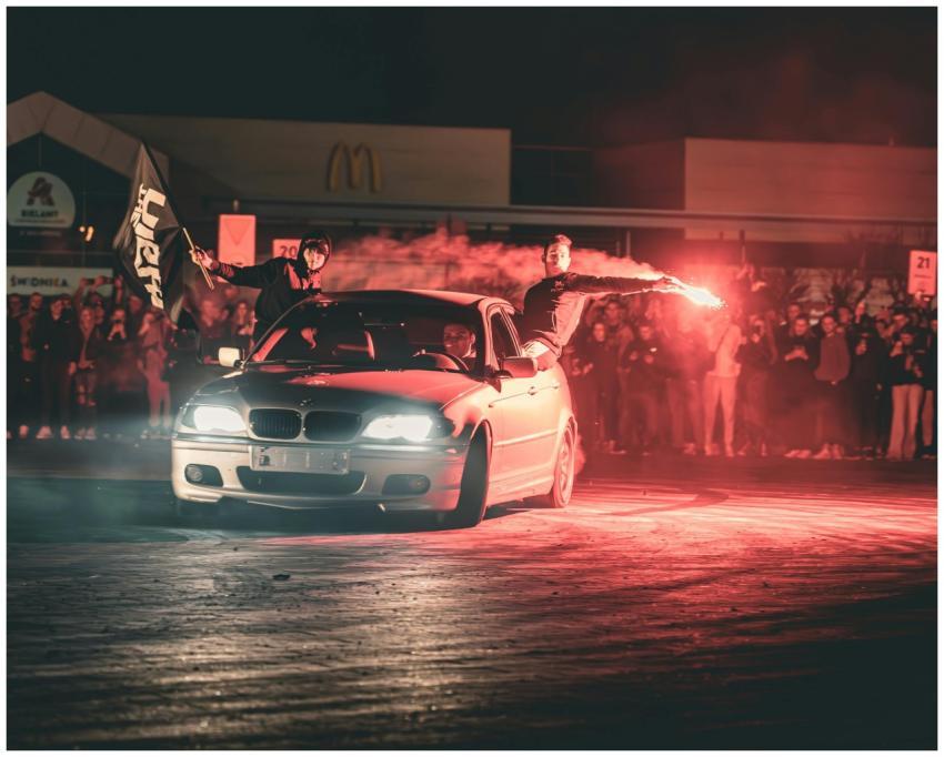 Exciting car stunt with flares and crowd at night
