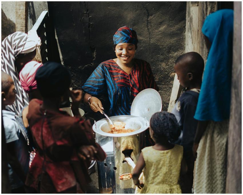 A woman serves food from a large pot to a group of