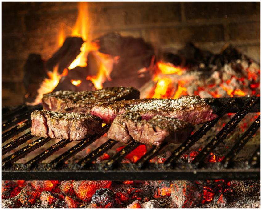 Succulent steaks grilling over hot coals and flame