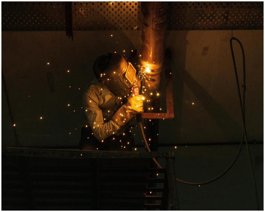 A welder at work indoors, creating bright sparks w