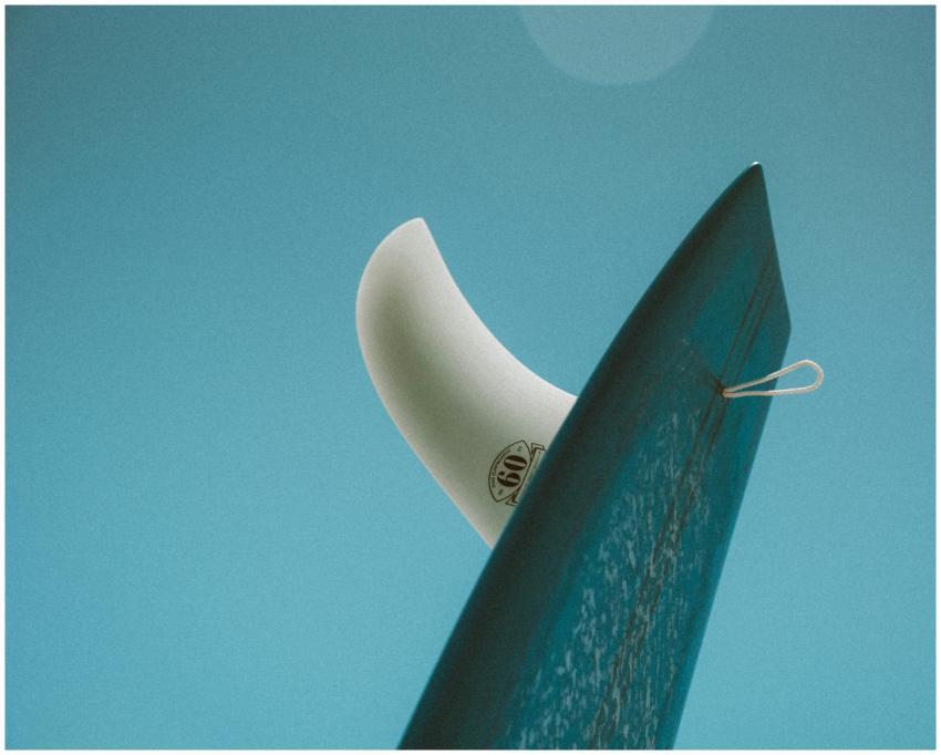 Close-up of a surfboard fin against a clear blue s