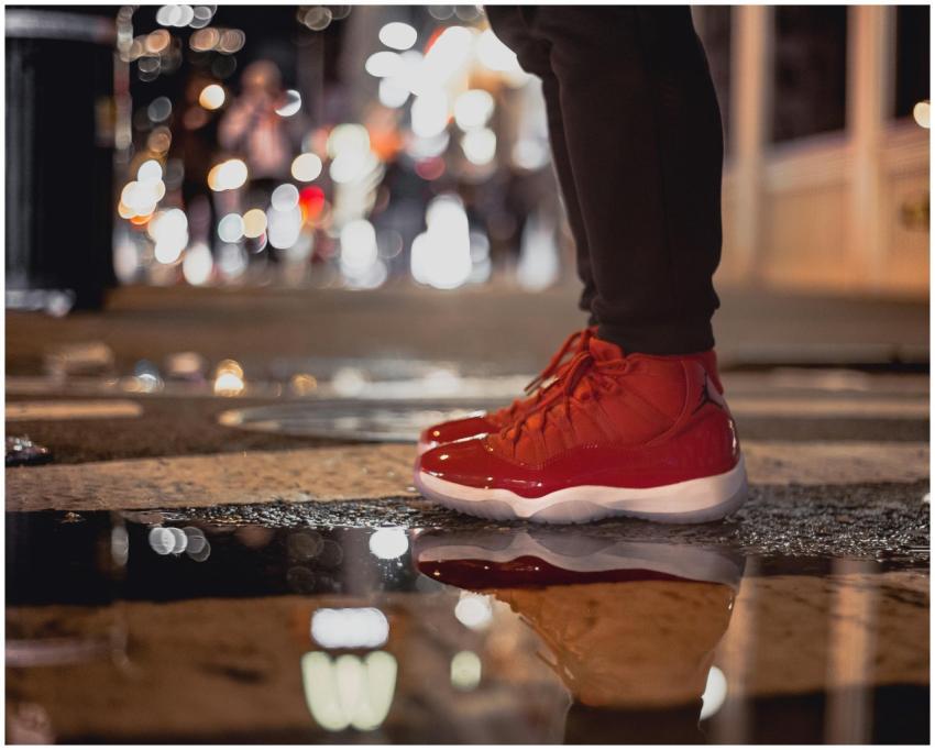 Stylish red sneakers on a wet urban street reflect