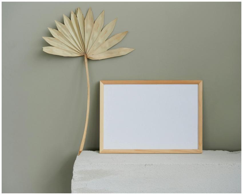 A wooden frame and dried palm leaf on a textured s