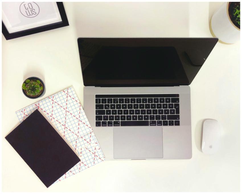 Minimalist workspace featuring a laptop, notepads,