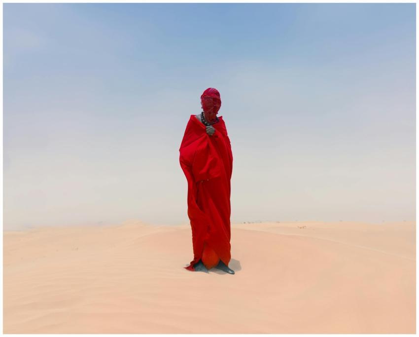 A person in red attire stands alone in a vast Afri