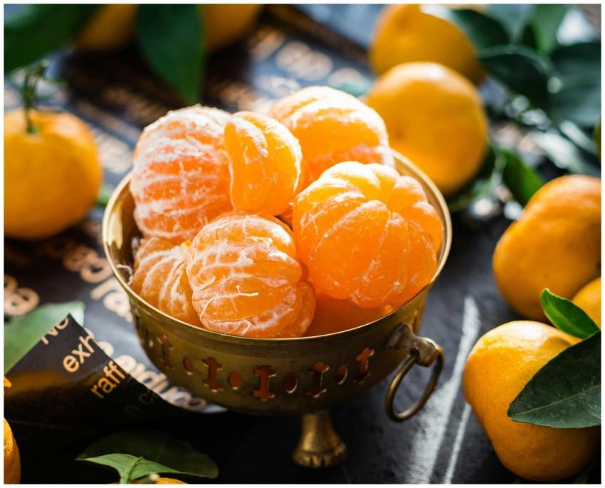Vibrant peeled and whole tangerines in a rustic bo