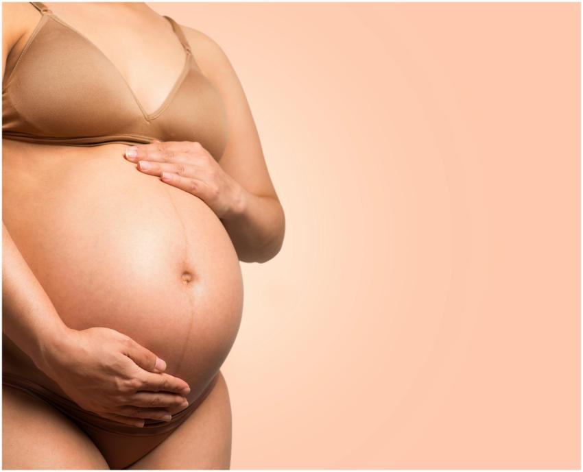 A pregnant woman gently cradles her belly, symboli