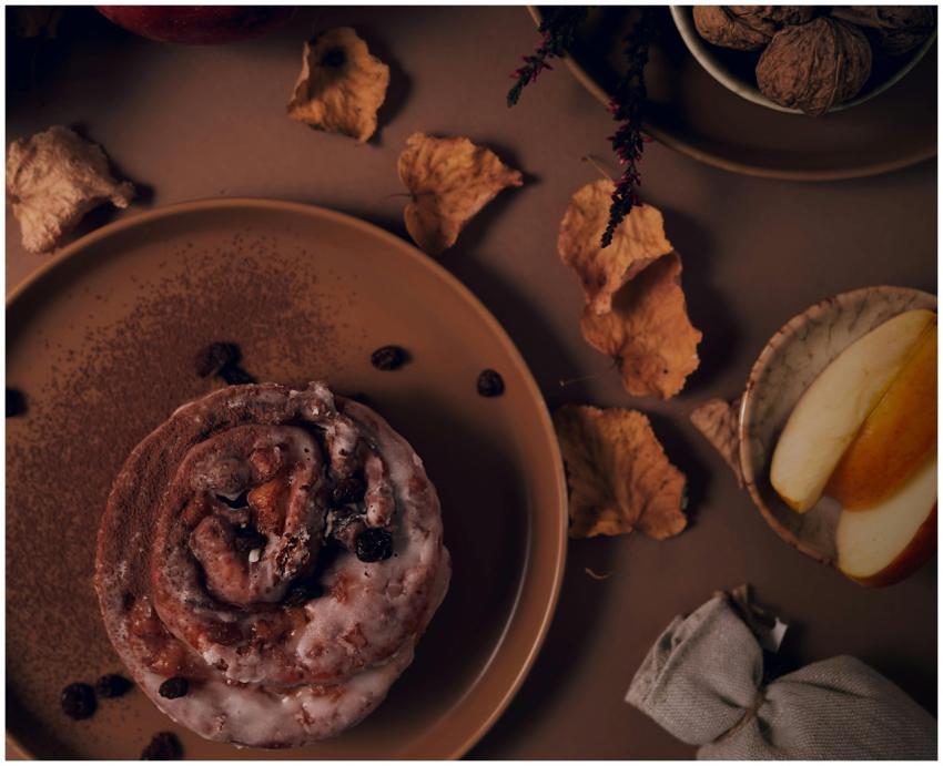 Rustic cinnamon roll surrounded by autumn leaves a