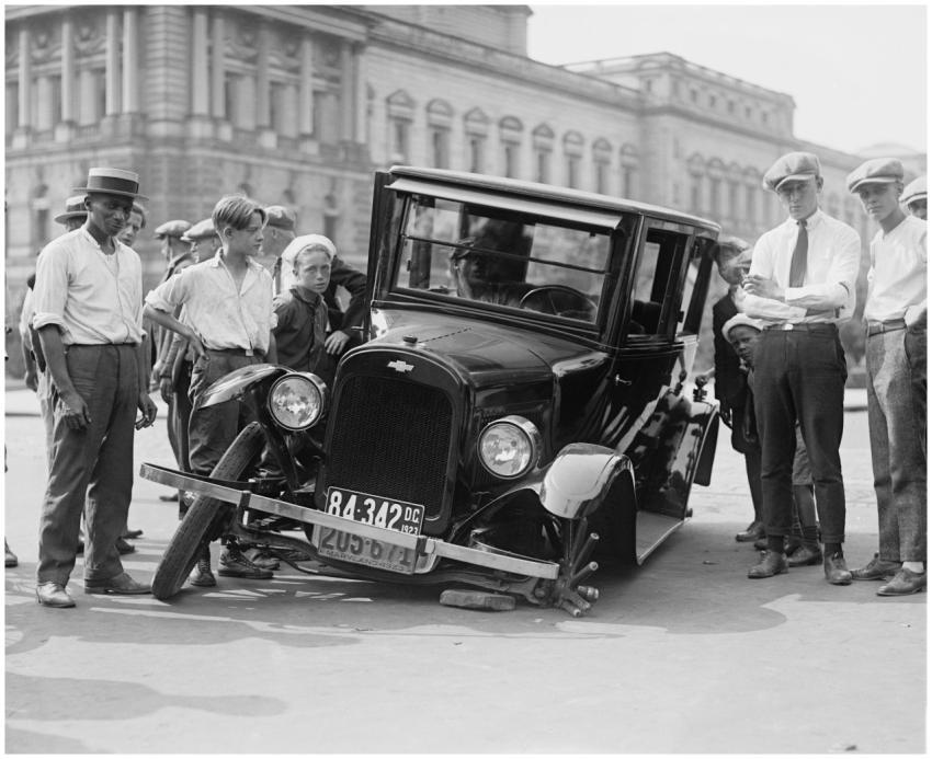 A vintage car crash attended by a group of onlooke