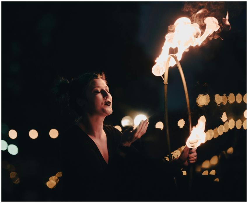 A performer elegantly manipulates flames in a capt