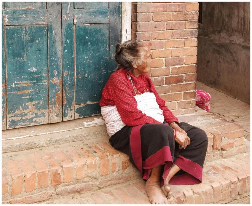 Elderly woman in traditional attire sitting by a r