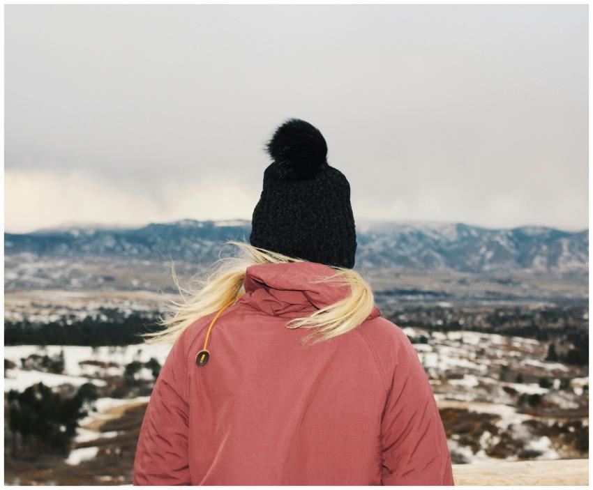 A woman in a pink jacket and beanie overlooks a sn