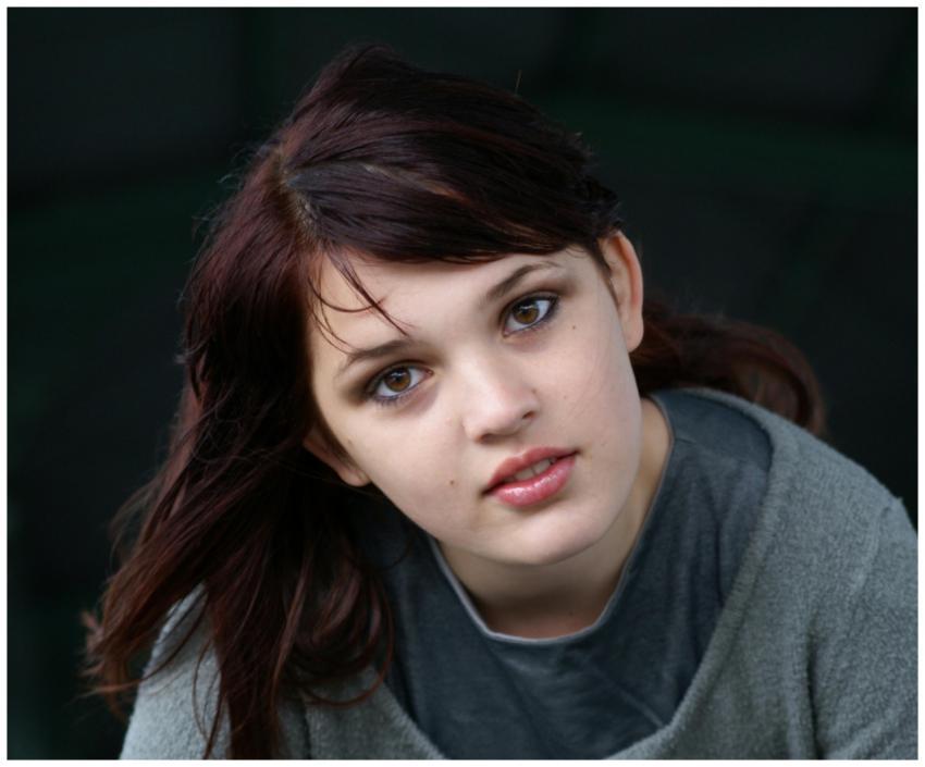 A close-up portrait of a young brunette woman with