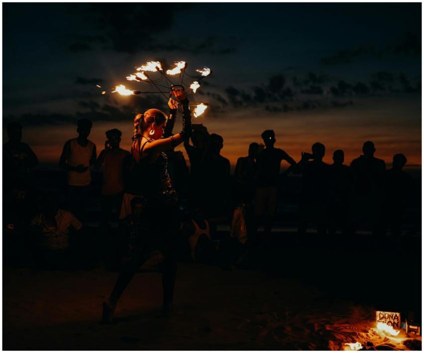 A mesmerizing fire dancer entertains a crowd at su
