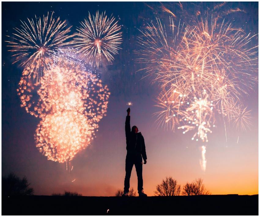 A person celebrates under vibrant fireworks in the