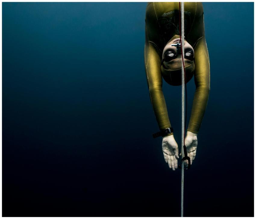 Freediver in wetsuit descends with rope in Bali's