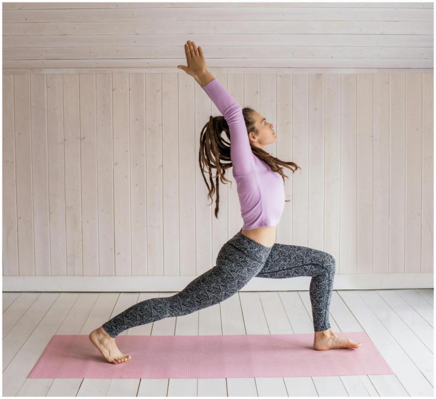 Woman in yoga pose indoors on pink mat wearing act