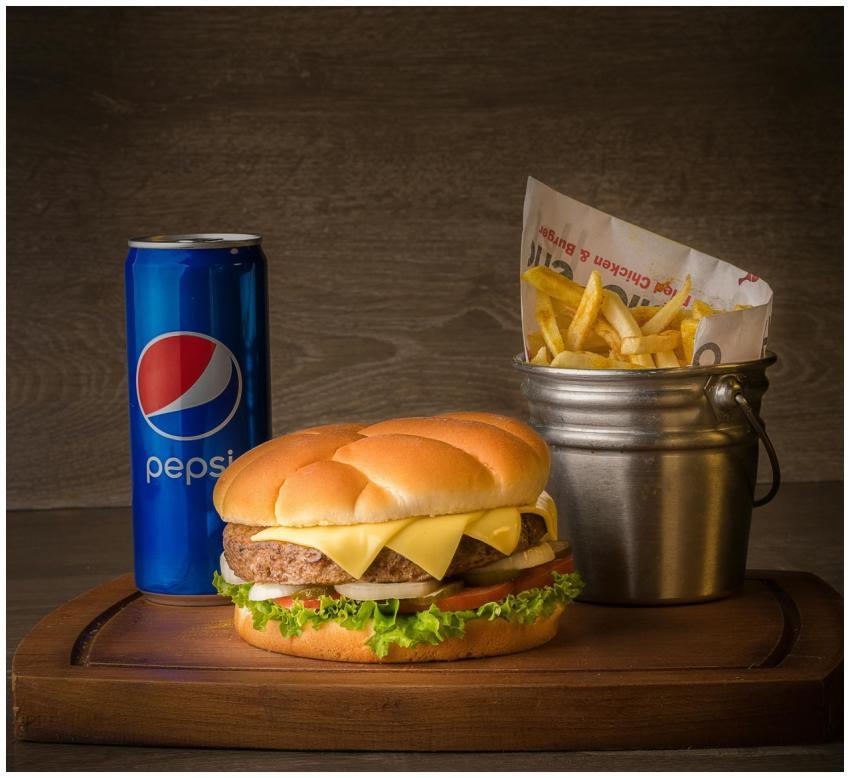 Appetizing cheeseburger served with fries and soda