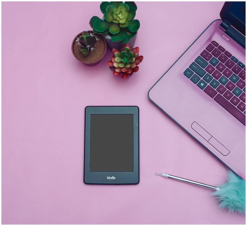 Flat lay of a modern desk setup with Kindle, lapto