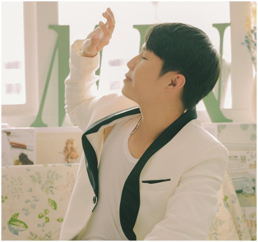 A young man in a chic white blazer enjoys sunlight