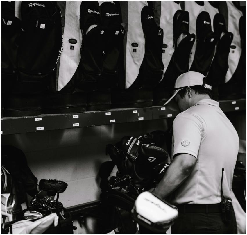 A golfer organizing multiple golf bags in a sports