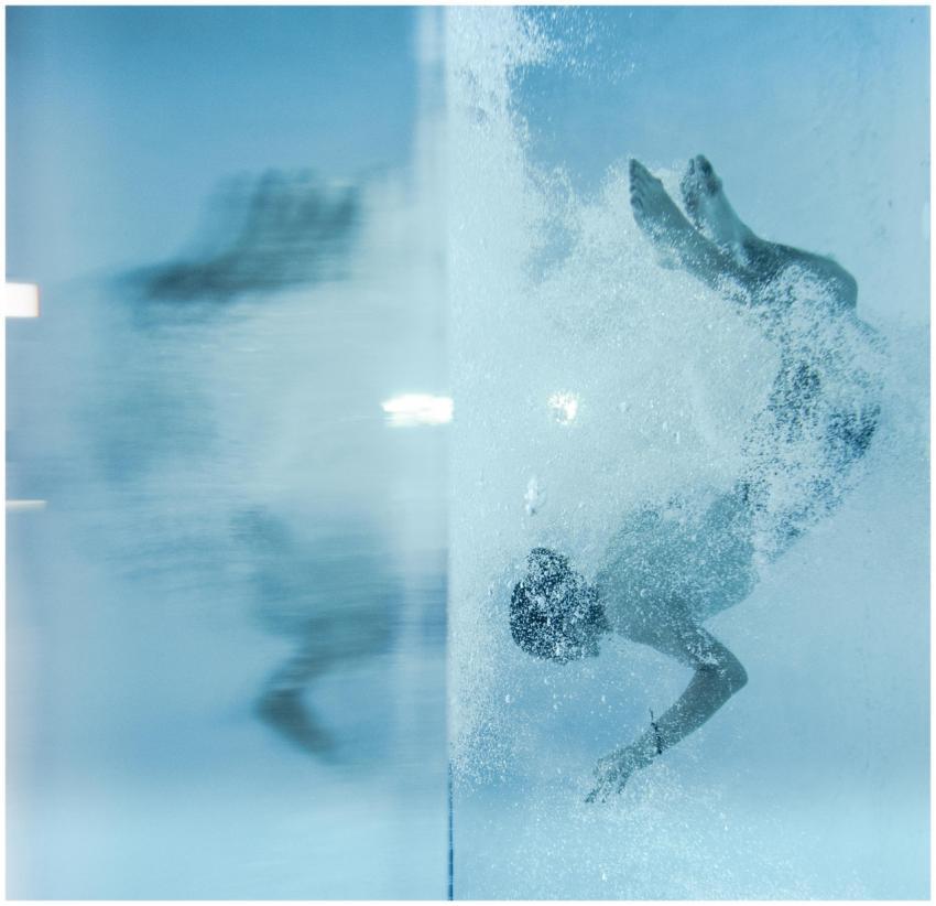 Person swimming underwater with air bubbles in a c