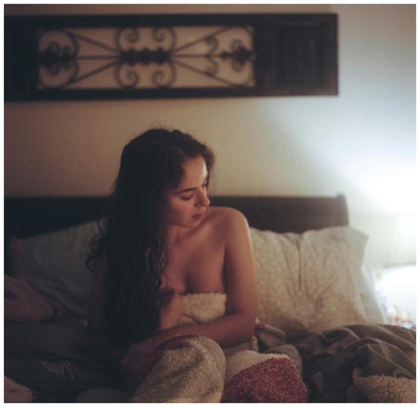 A woman relaxes in a dimly lit bedroom wrapped in