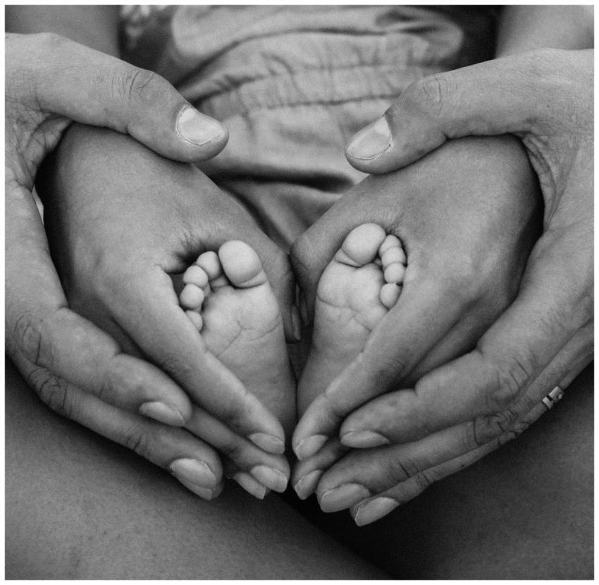 Black and white photo of adult hands cradling baby