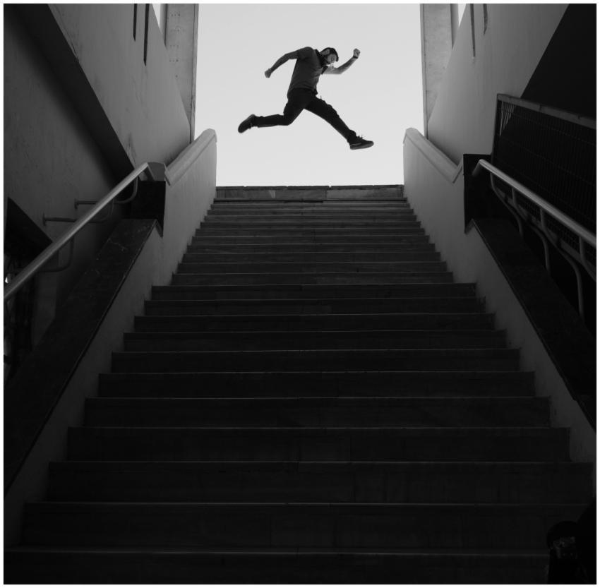 Silhouette of a man performing parkour jump over s