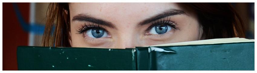 Close-up of a woman with blue eyes peeking over a