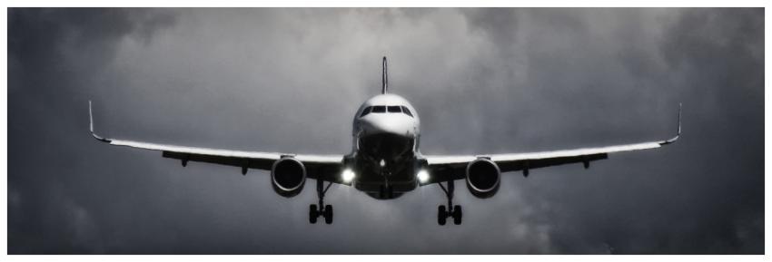 A dramatic view of an airplane landing with stormy
