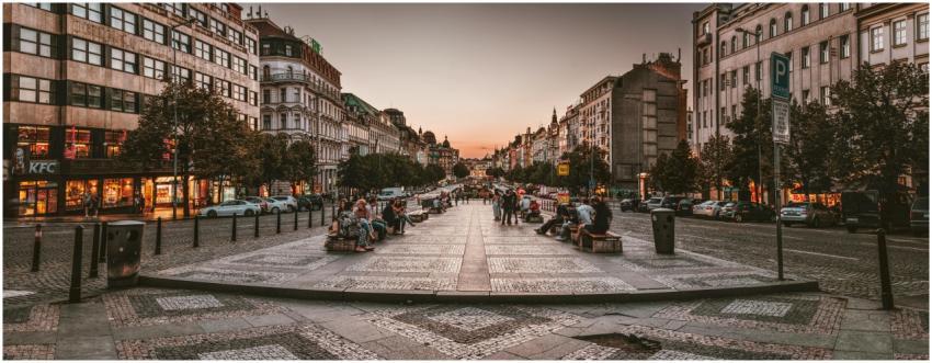 A bustling urban street in Prague at sunset, featu