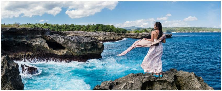 Woman in a flowing dress admiring the ocean view f