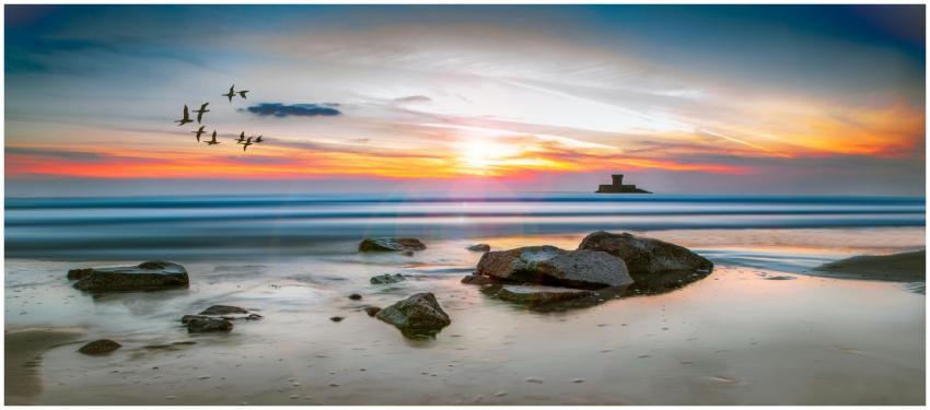 Beautiful sunset on a Jersey beach with rocks, bir