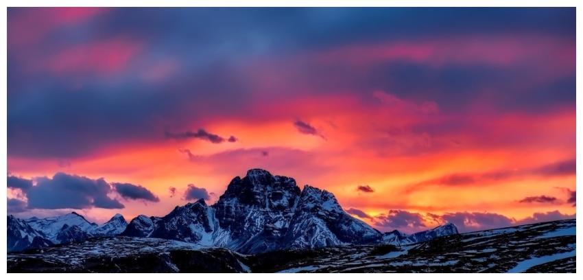 Vibrant sunset over snow-capped mountains with a v