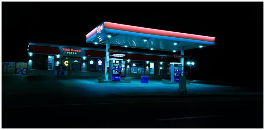 A brightly lit gas station with vibrant signage gl