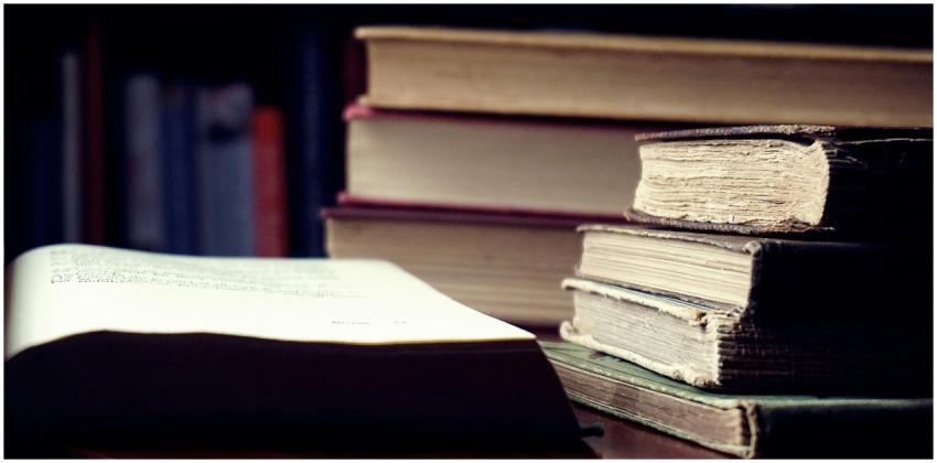 A stack of vintage hardcover books in a dimly lit