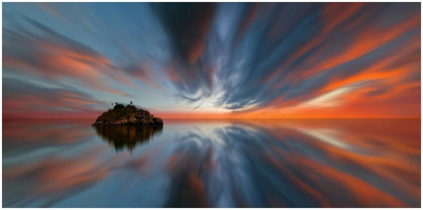 A tranquil island reflects on calm waters at sunse