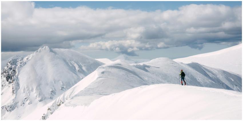 A lone skier traverses snow-covered peaks under a