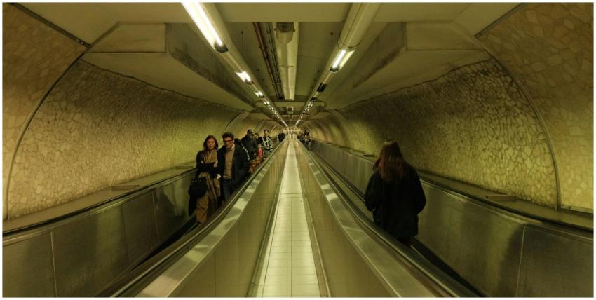 A busy underground tunnel with commuters on escala