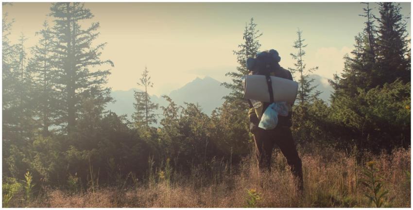 A lone hiker with a backpack and sleeping mat in a